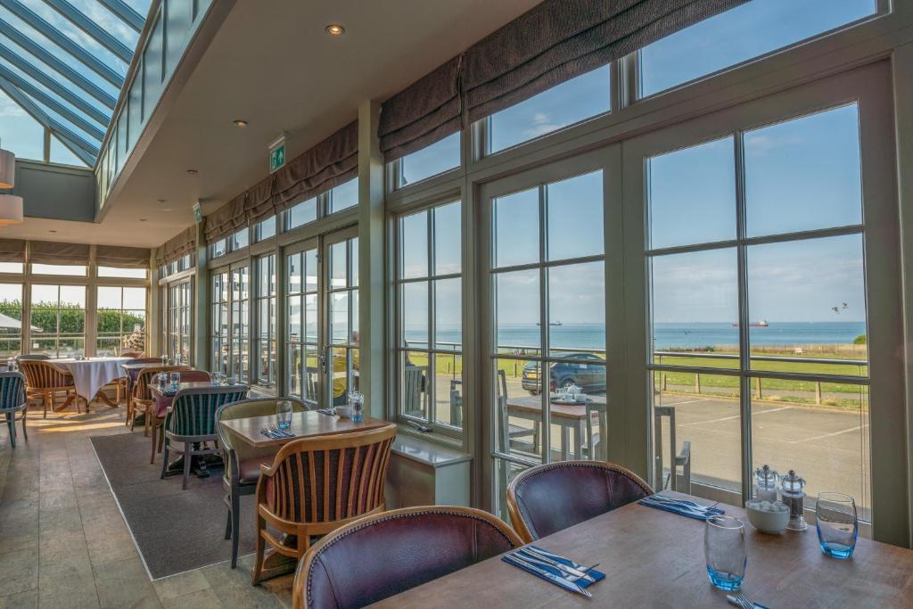 a restaurant with tables and chairs and large windows at Botany Bay Hotel in Broadstairs
