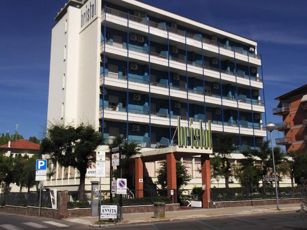 - un grand bâtiment blanc avec un panneau devant dans l'établissement Hotel Bristol, à Cervia