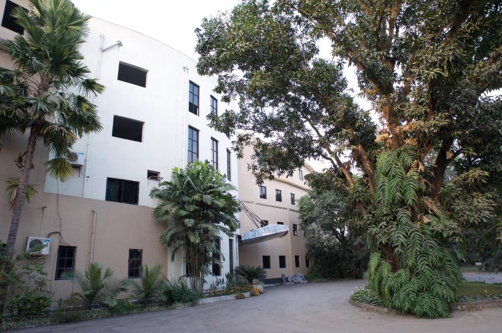 duży biały budynek z drzewami przed nim w obiekcie Central Palm Hotel w Bharatpur