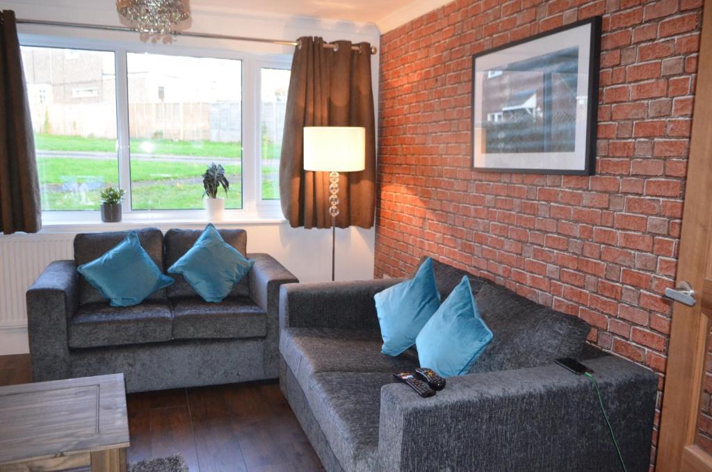 a living room with two couches and a brick wall at Mundy House in Swindon