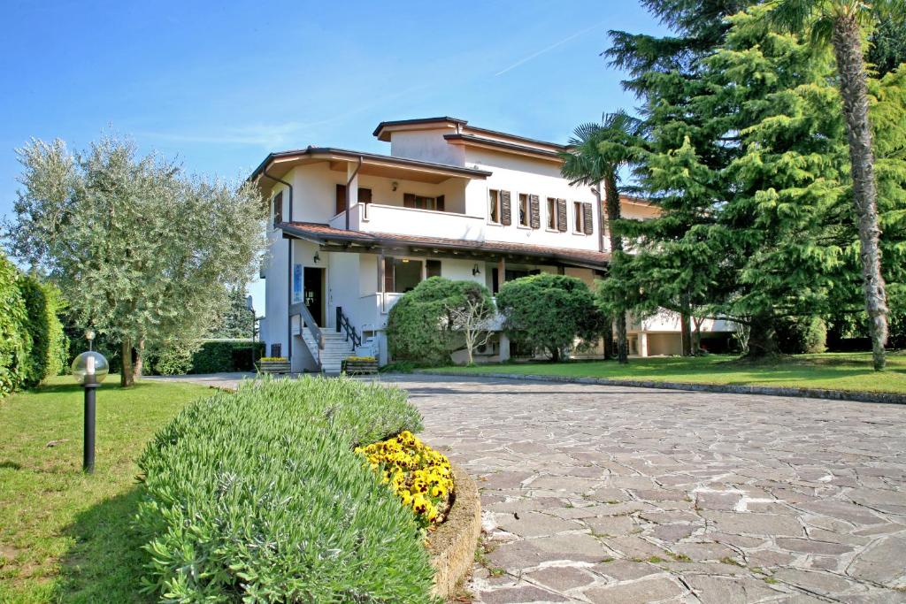 una gran casa blanca con árboles y entrada en Relais BB Pacengo, en Lazise