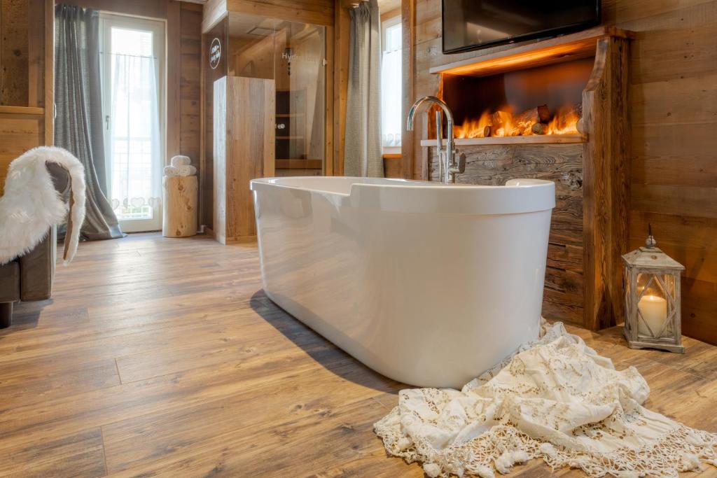 bañera blanca en una habitación con chimenea en John Luxury Suites, en Folgaria