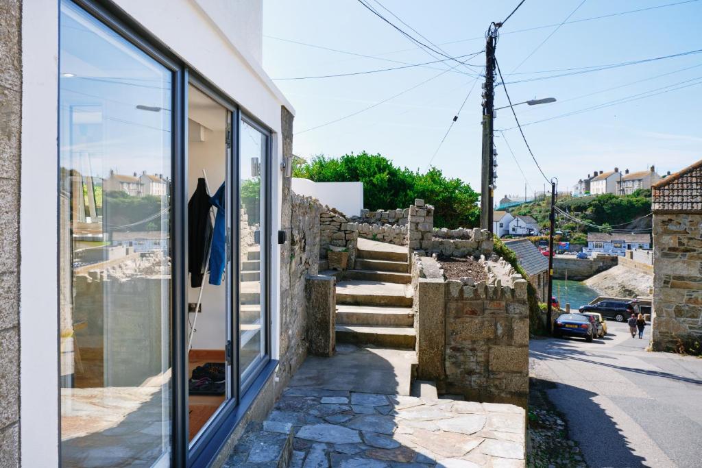 a house with a stone wall and stairs next to a building at Finest Retreats - Luxury Holiday Let in Porthleven, Sleeping 2 in Porthleven