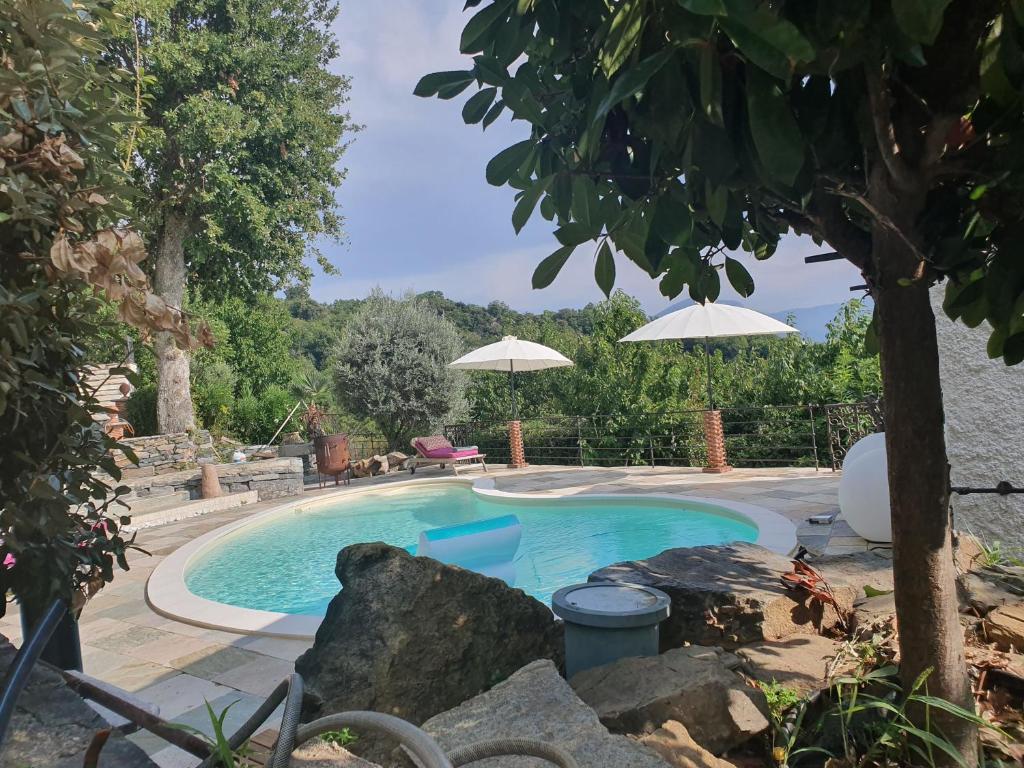 - une piscine dans une cour avec un parasol dans l'établissement maison de charme avec piscine et vue exceptionnelle, à Scolca