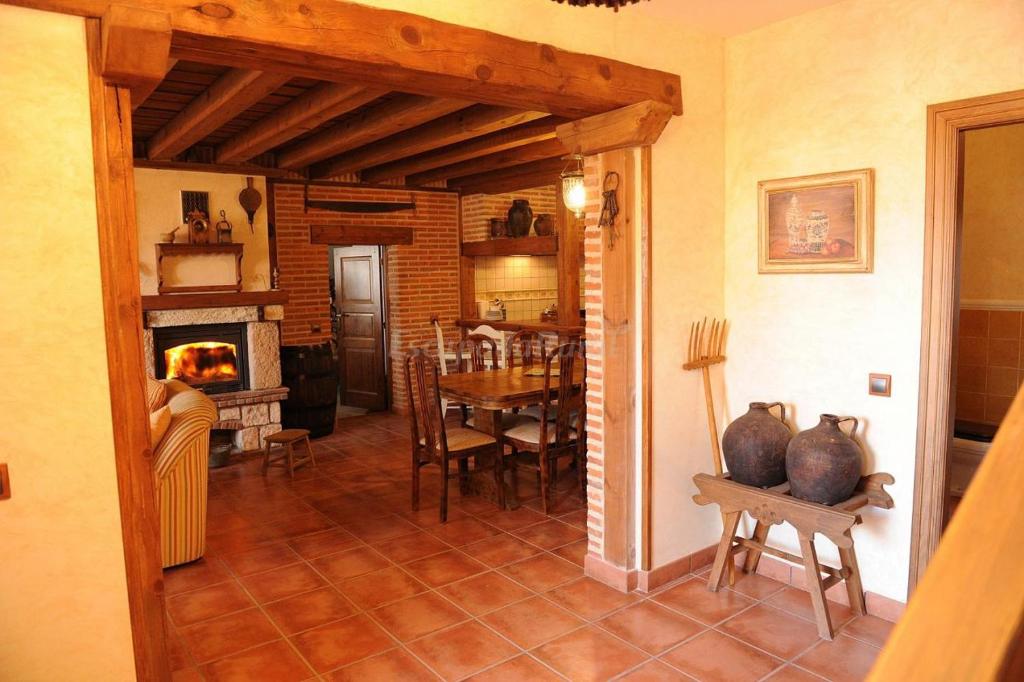 a kitchen and dining room with a table and a fireplace at Casa Rural El Capricho in Otero de Herreros