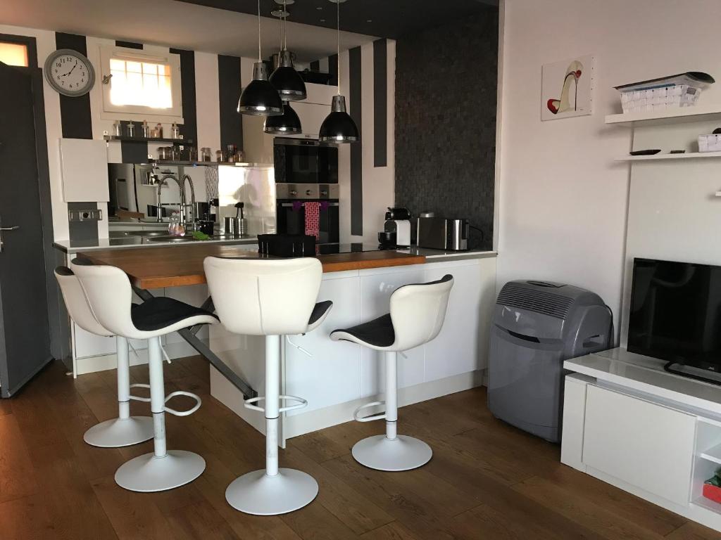 een keuken met witte barkrukken en een aanrecht bij Gruissan Pleine vue sur port in Gruissan