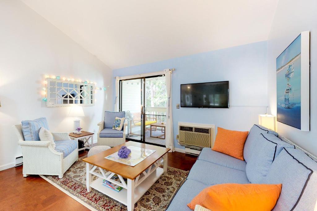 sala de estar con sofá azul y sillas en Ocean Mandevilla, en Brewster