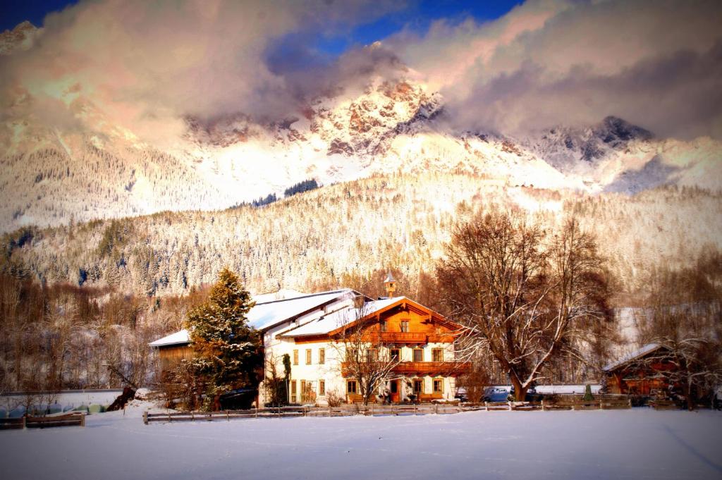 a house in the snow in front of a mountain at Untermühlbauer Fam. Schreder in Saalfelden am Steinernen Meer