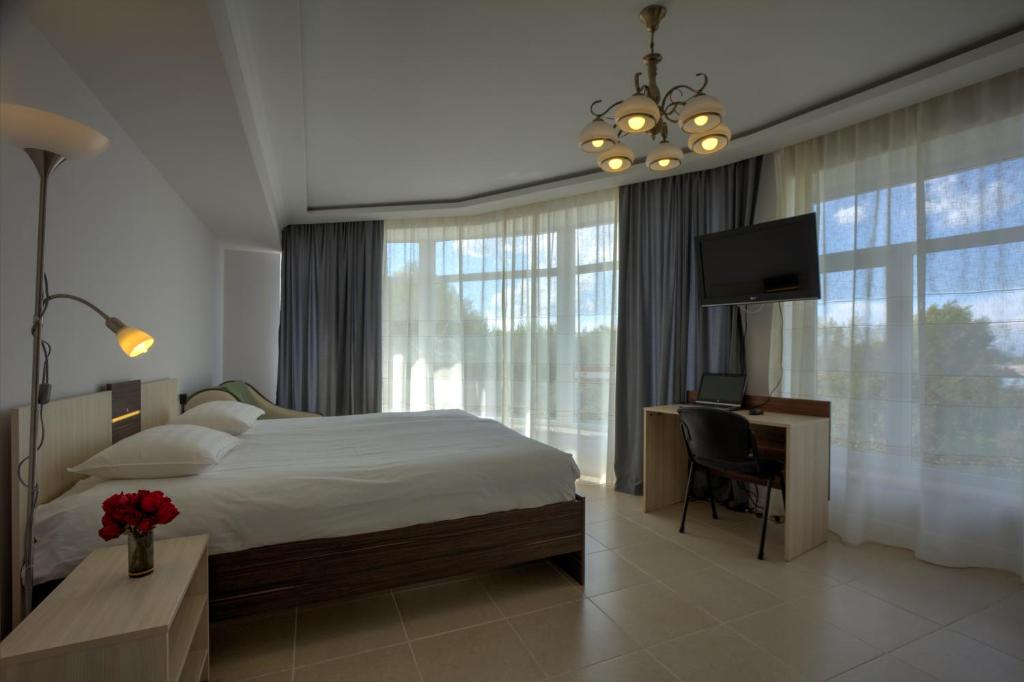 فندق غرين يارد في كاراكول: غرفة نوم بسرير ومكتب وتلفزيون