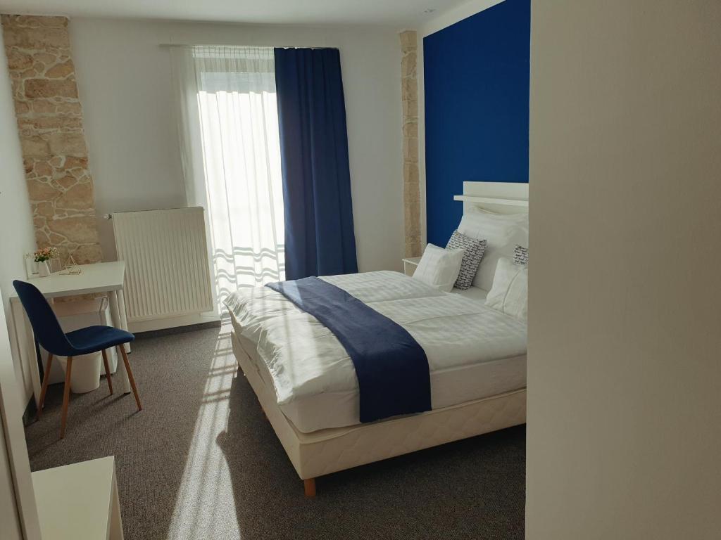 a bedroom with a bed and a desk and a window at Szitakötő Panzió in Fertőrákos