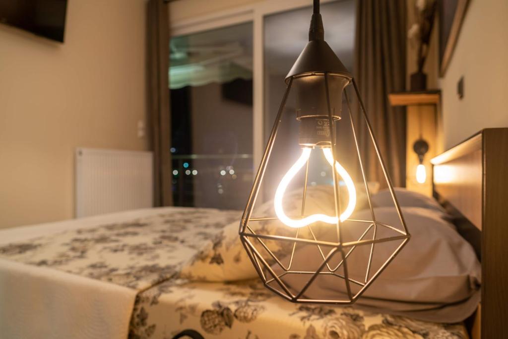 eine Glühbirne in einem Käfig, der über einem Bett hängt in der Unterkunft First View Apartment in Kateríni