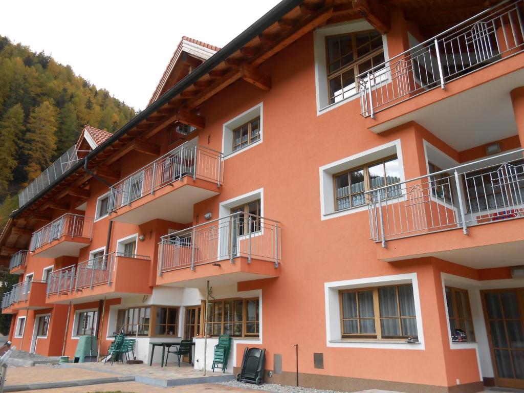 un edificio naranja con balcones y mesas delante de él en Appartement beim Brunnen 10, en Sölden