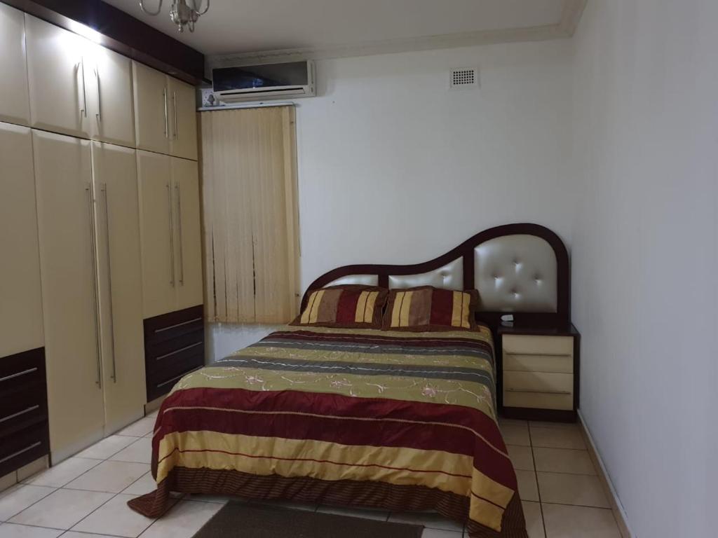 1 dormitorio con 1 cama con manta a rayas en Angela's Place, en Durban
