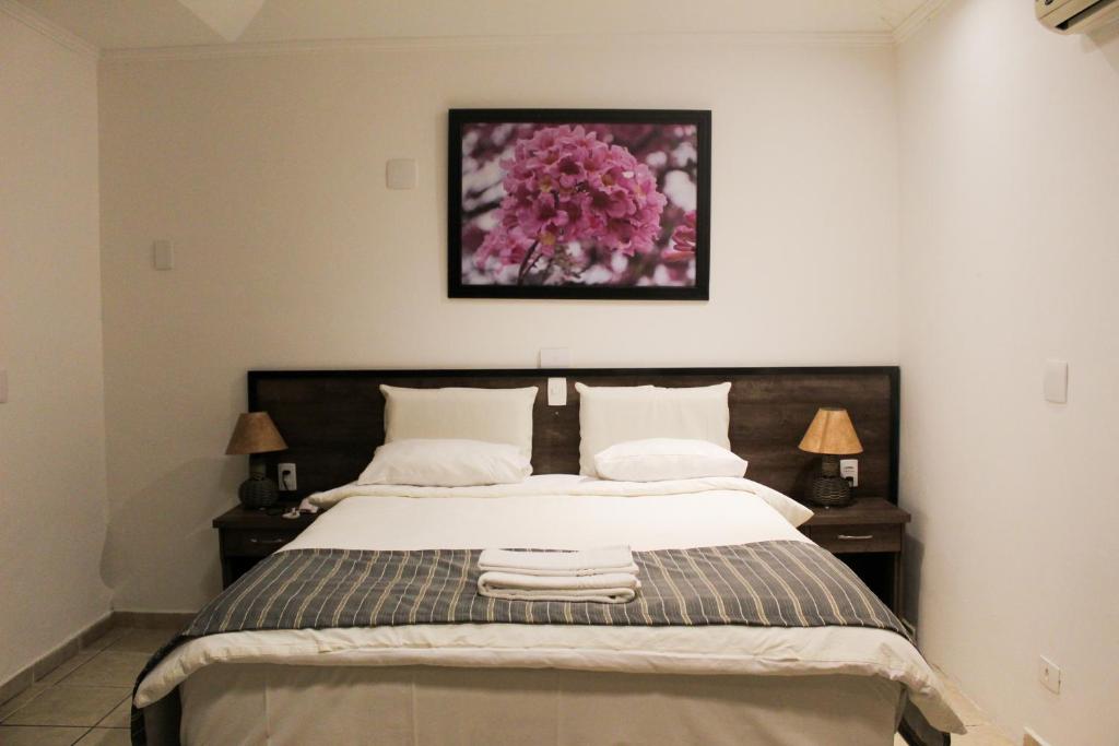 a bedroom with a large bed with two lamps and a picture at Hotel Brisa do Japi in Cabreúva