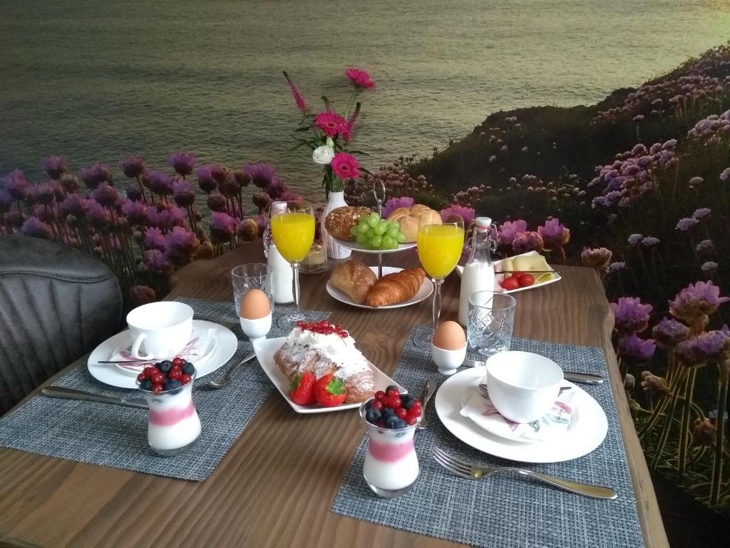 - une table avec des aliments pour le petit-déjeuner, des boissons et des fleurs dans l'établissement Bed & Breakfast Ons Nest, à Westwoud