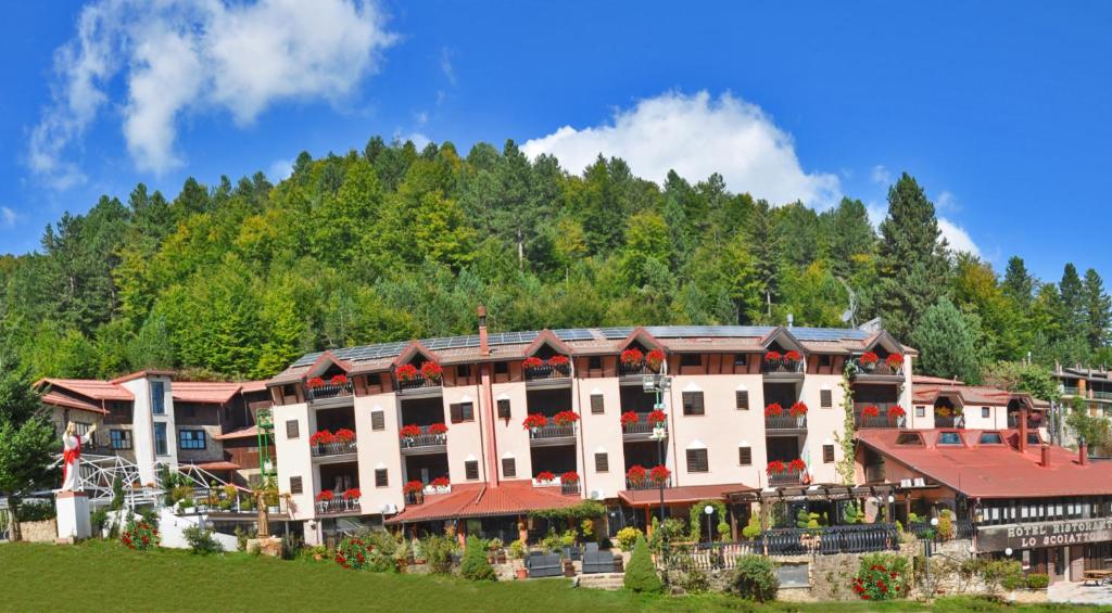 a large building with flowers in front of a mountain at Hotel Lo Scoiattolo in Cotronei