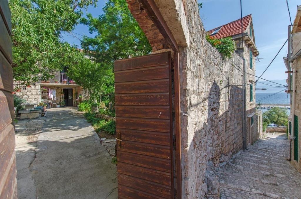 eine alte Holztür an einer Steinmauer in einer Straße in der Unterkunft Apartments Jerkica - 50 m from sea in Sutivan