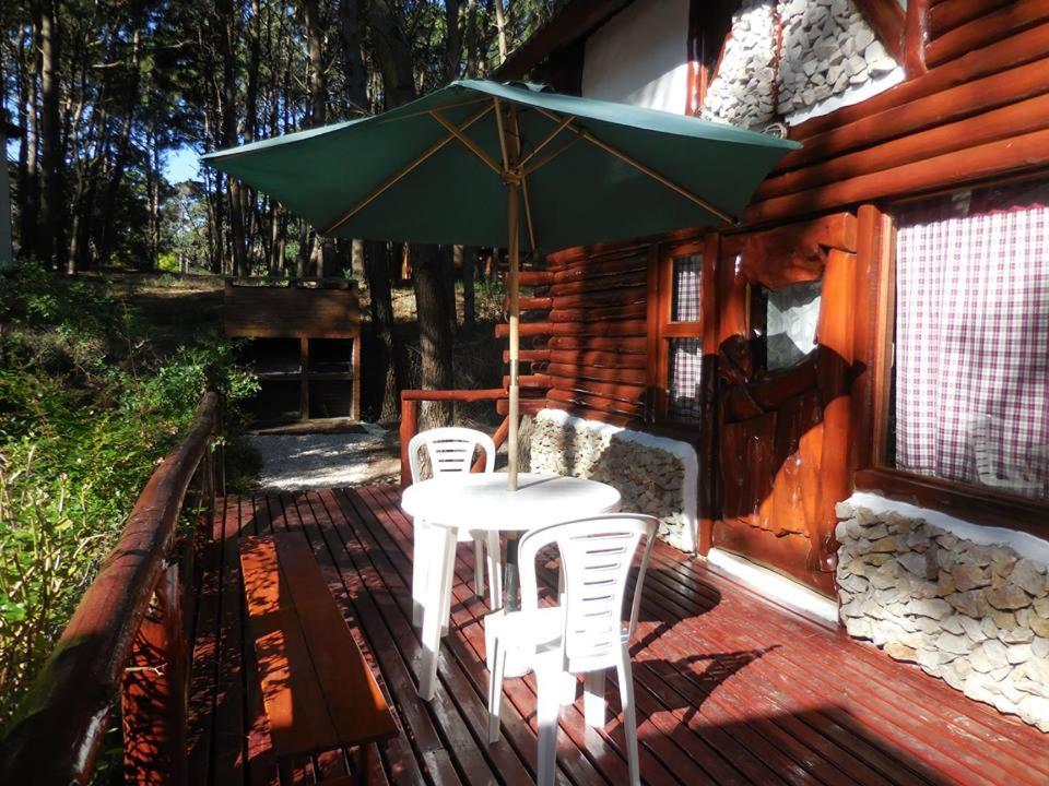 una mesa y sillas en una terraza con sombrilla en Cabañas Rupel a 3 cuadras del mar en Balneario Mar Azul