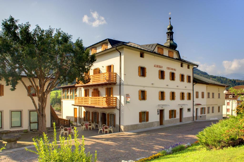 Treppo CarnicoにあるAlbergo Cristofoliのバルコニーと木がある白い大きな建物