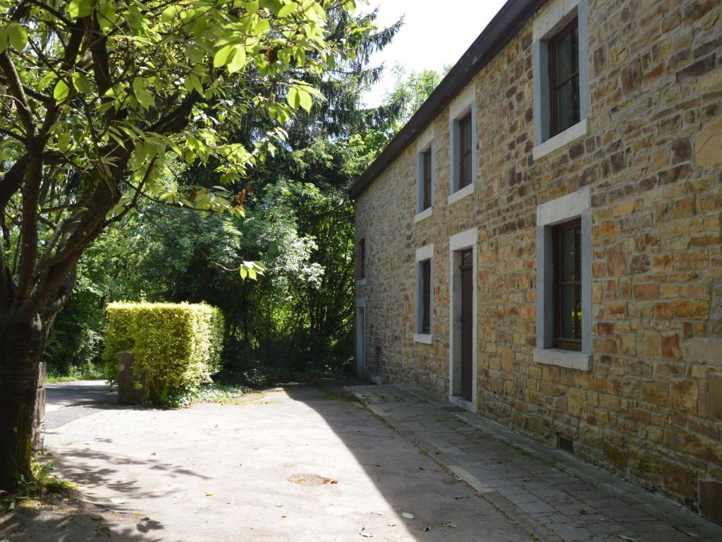 a brick building with a tree next to a sidewalk at This plain house is very suitable for groups in Ferrières