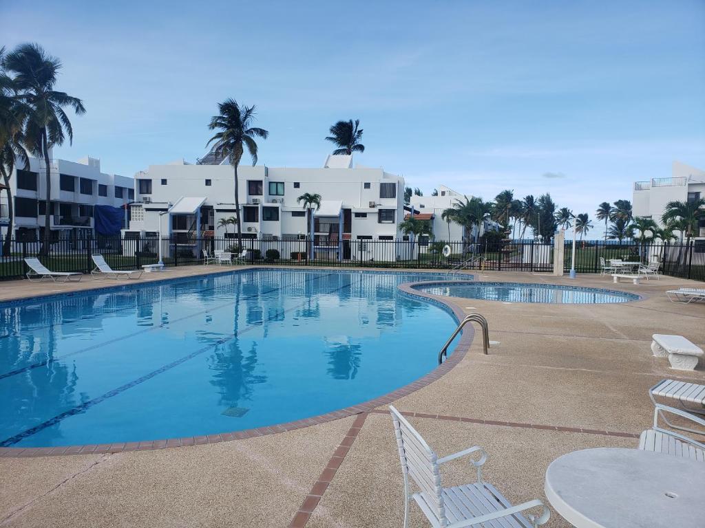 a large swimming pool with chairs and palm trees at Relax Beachfront Complex at Rio Grande in Rio Grande
