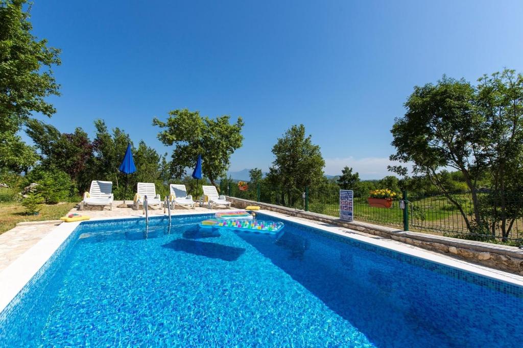 a swimming pool with blue water and chairs and trees at Villa Josip - private swimming pool in Labin