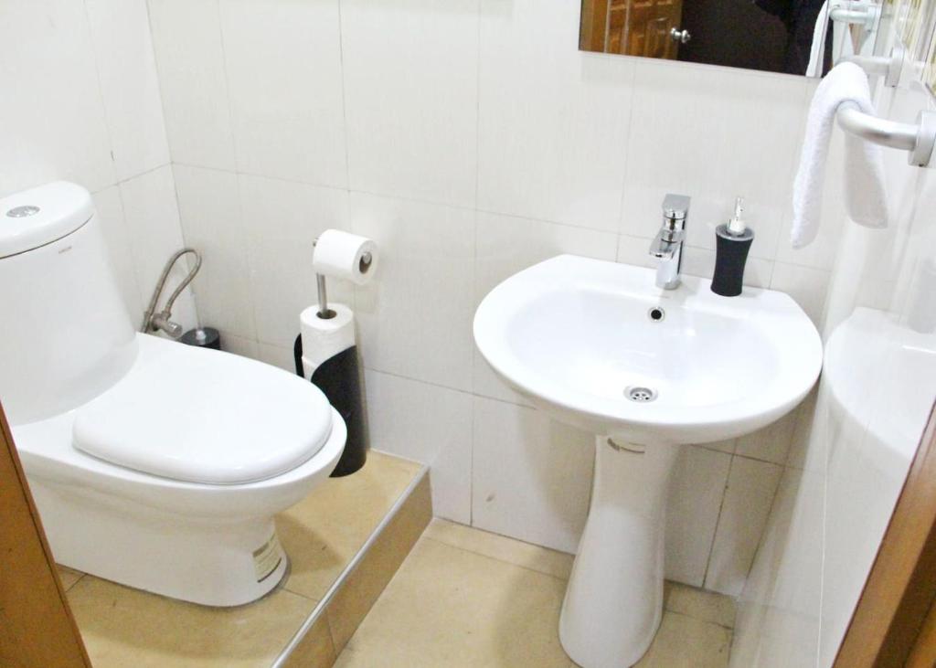 een witte badkamer met een toilet en een wastafel bij The Urban Space in Accra