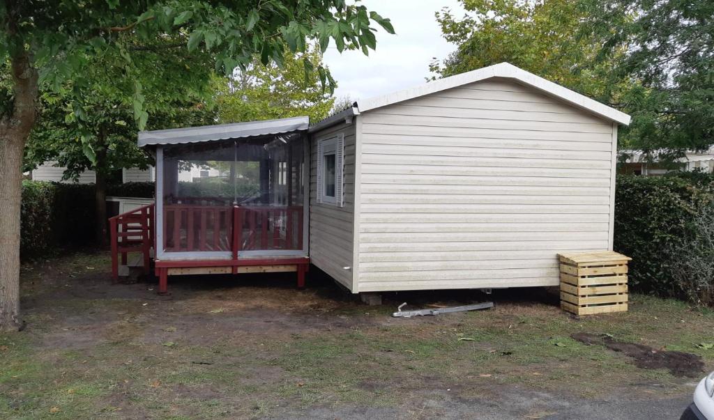 a small white shed sitting in a yard at 3 chambres mimizan gastes biscarrosse camping siblu in Gastes