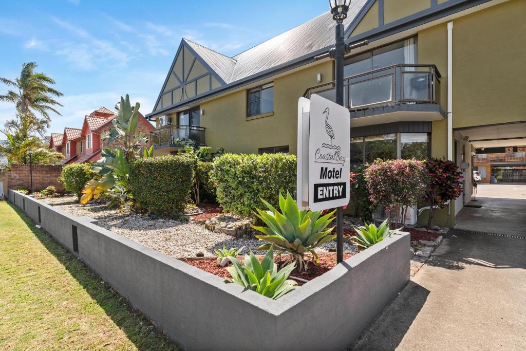 una señal frente a un edificio con entrada al patio en Coastal Bay Motel, en Coffs Harbour