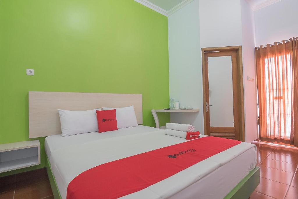 um quarto com uma cama grande e um cobertor vermelho em RedDoorz Plus near Alun Alun Kuningan em Kuningan