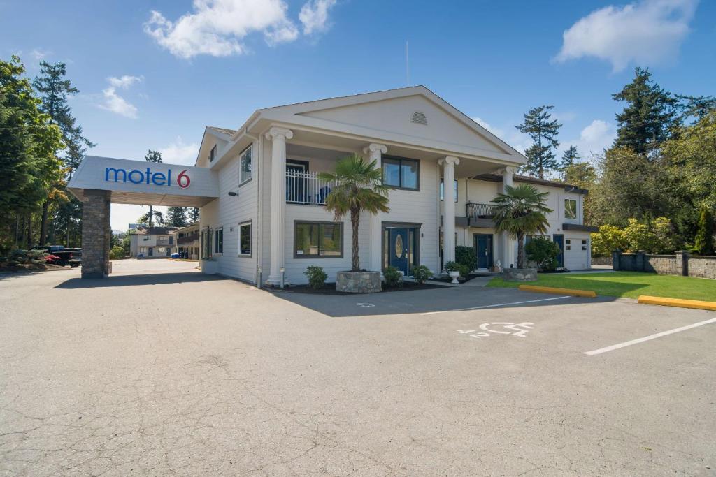 a large white building with a sign in a parking lot at Motel 6-Saanichton, BC - Victoria Airport in Saanichton