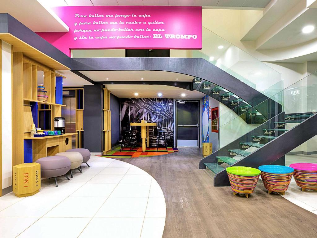 a lobby with a staircase and a table and chairs at Ibis Styles Mexico Reforma in Mexico City