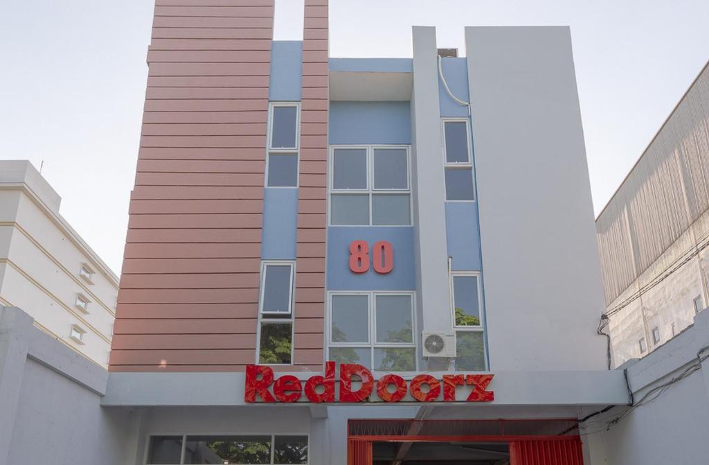 een gebouw met een rood bord ervoor bij RedDoorz Plus Syariah @ Raya Nginden 2 in Surabaya