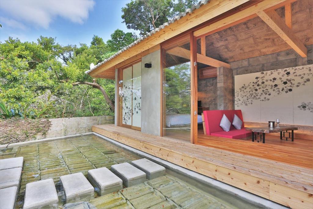 an outdoor patio with a red chair and a table at KAWASEMINOSU (MUKAKA VILLA) in Nago