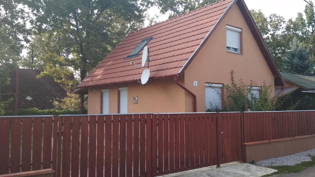 ハイドゥーナーナーシュにあるNánás Szállásの赤い屋根の柵の裏の家