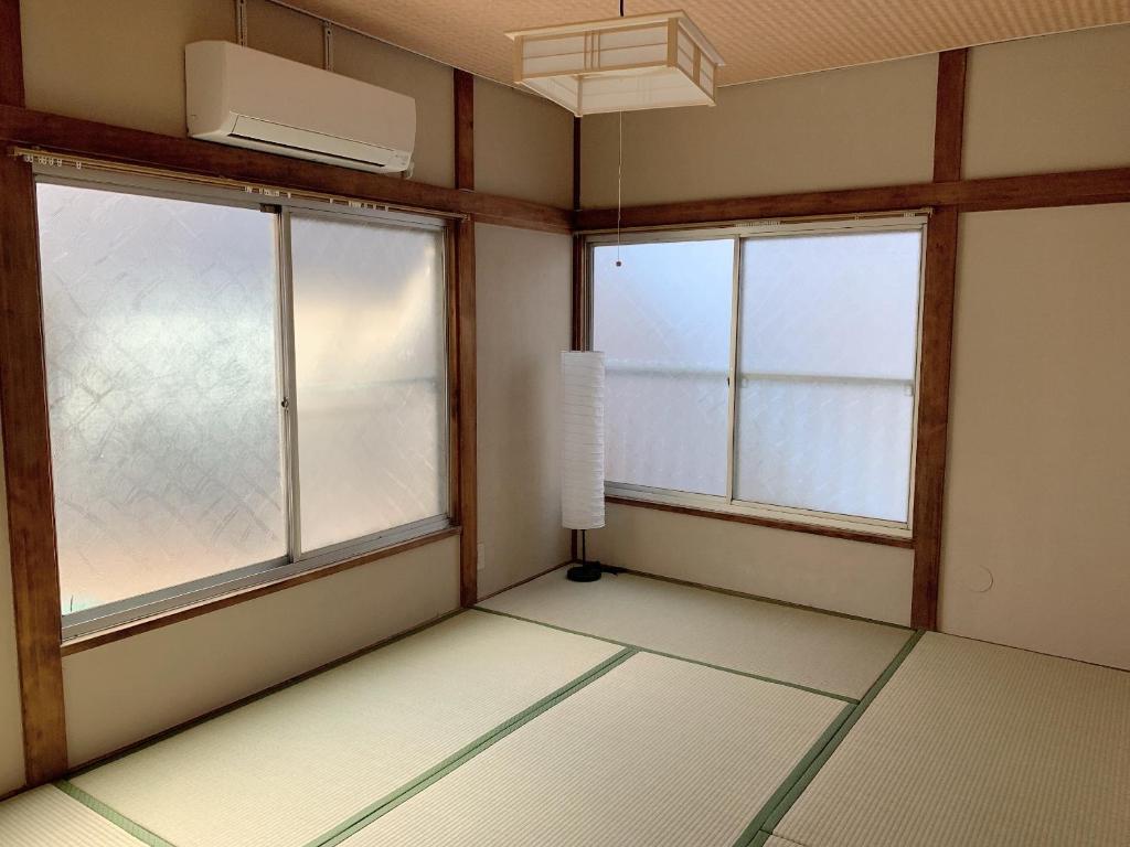 Habitación vacía con 2 ventanas y ventilador. en Vivian house en Tokio