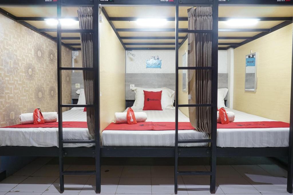 two bunk beds with red pillows in a room at RedDoorz Hostel @ Borobudur Street in Blimbing