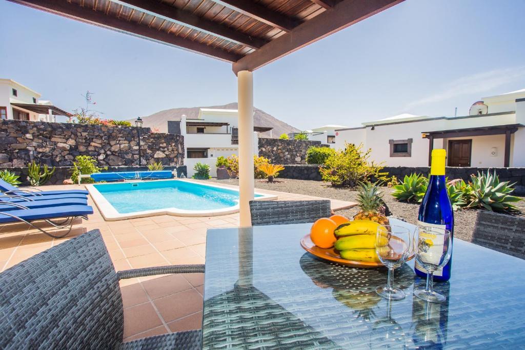 - une table avec une assiette de fruits et une bouteille de vin dans l'établissement Eslanzarote Villa Eleonor, Super Wifi, Heated Pool, Sat tv, à Playa Blanca