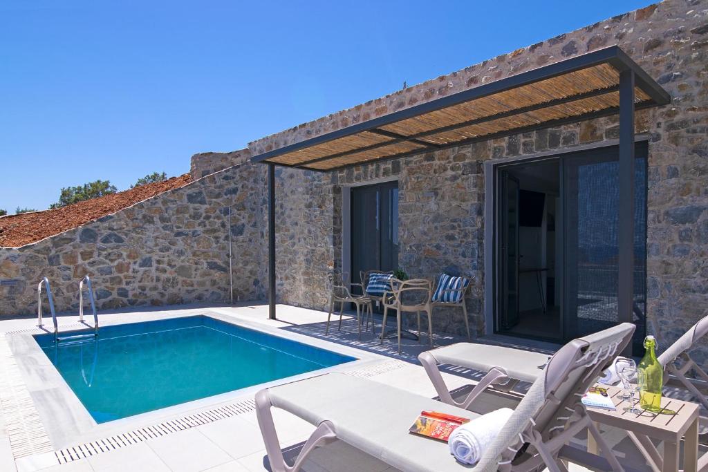 a villa with a swimming pool and a patio at Varkotopi Villas in Agios Pavlos