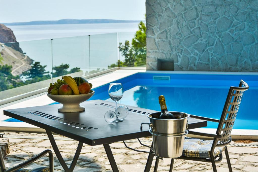 a table with a bowl of fruit and a wine glass at Villa Degenija - Principality of Zarijak in Jablanac