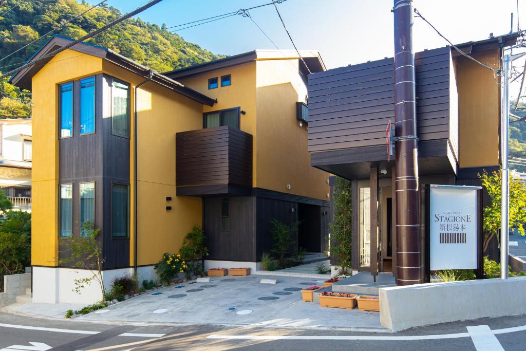 un bâtiment jaune avec un panneau sur le côté d'une rue dans l'établissement Stagione Hakone Yumoto, à Hakone