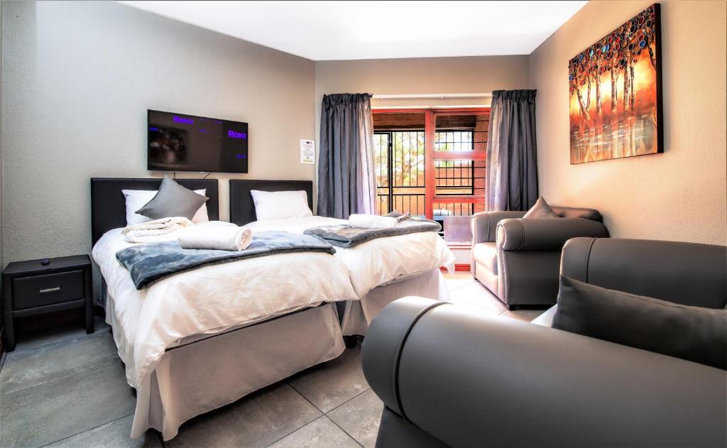 a bedroom with a bed and two chairs and a tv at JoziStay @ Savannah Apartments in Little Falls
