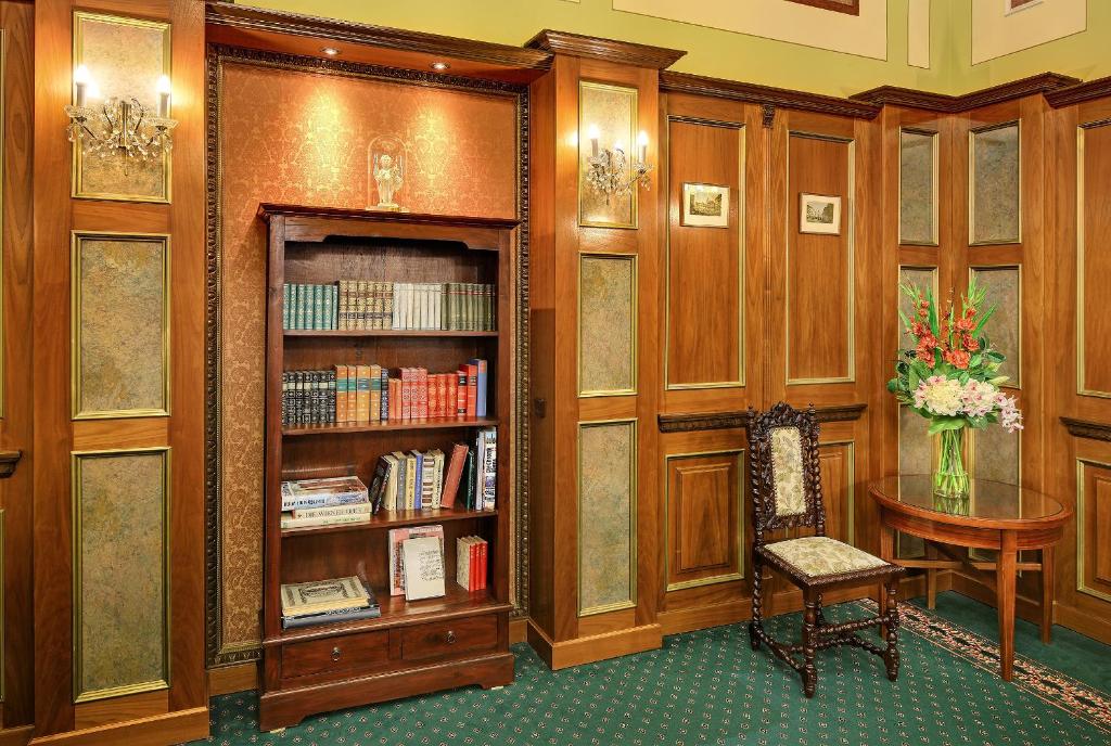 biblioteka z drewnianymi półkami na książki, stołem i krzesłem w obiekcie Hotel Bellevue Wien w Wiedniu