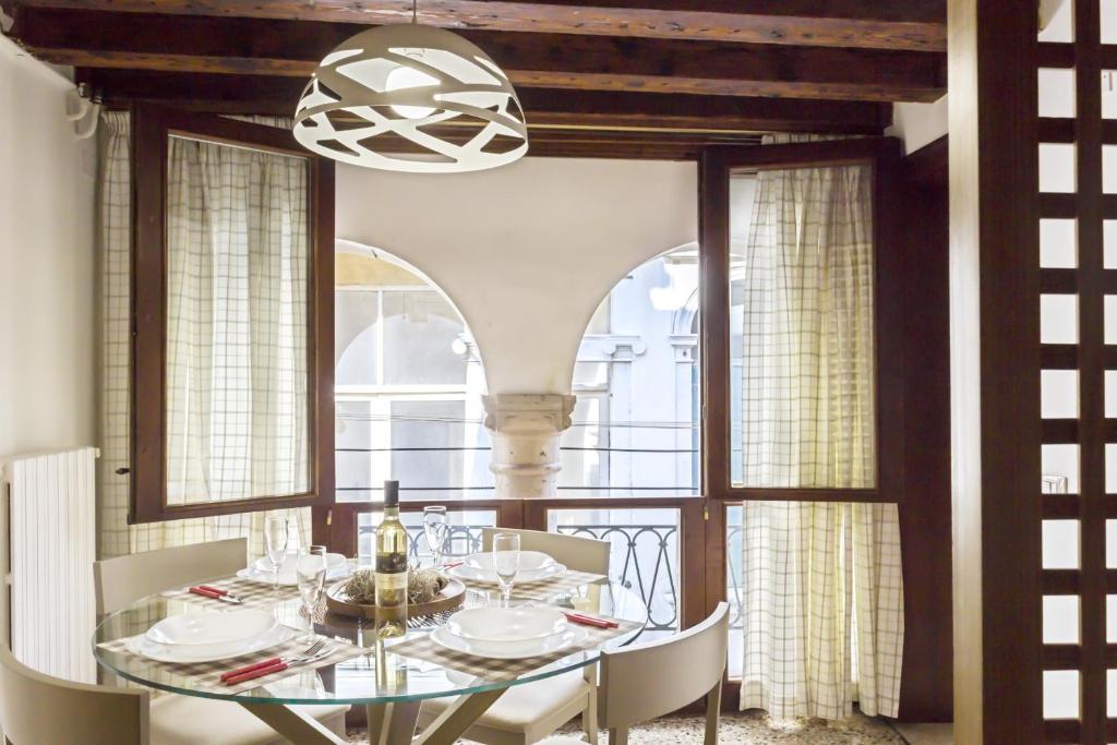 une salle à manger avec une table et des chaises en verre dans l'établissement Rialto Corte dei Sansoni canal view, à Venise