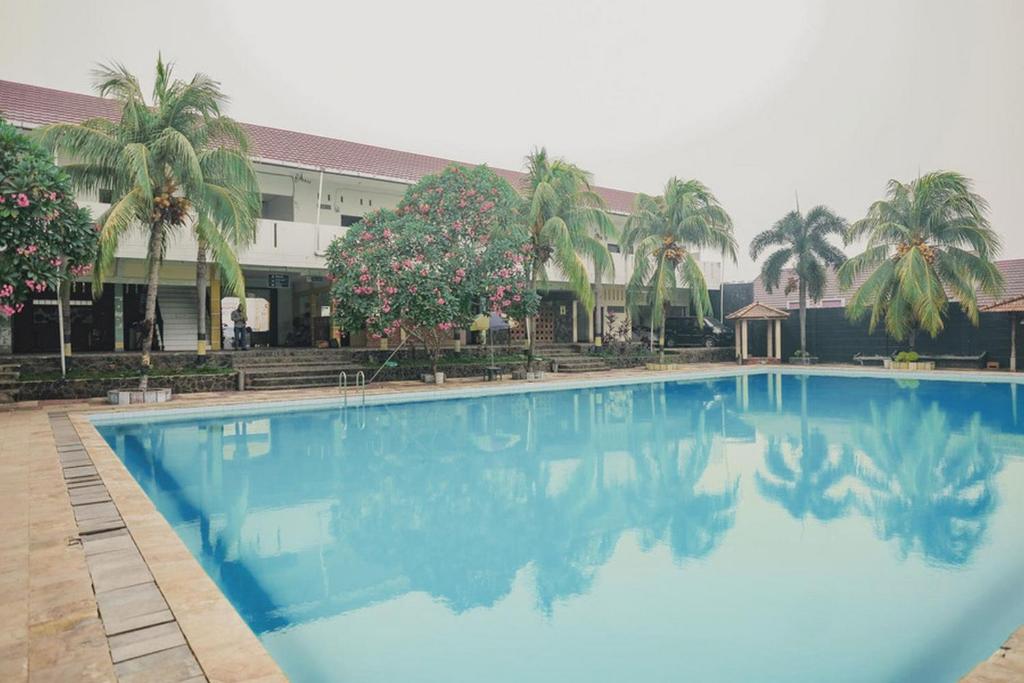 a large blue swimming pool in front of a building at RedDoorz Syariah @ Pasir Putih Jambi in Jambi