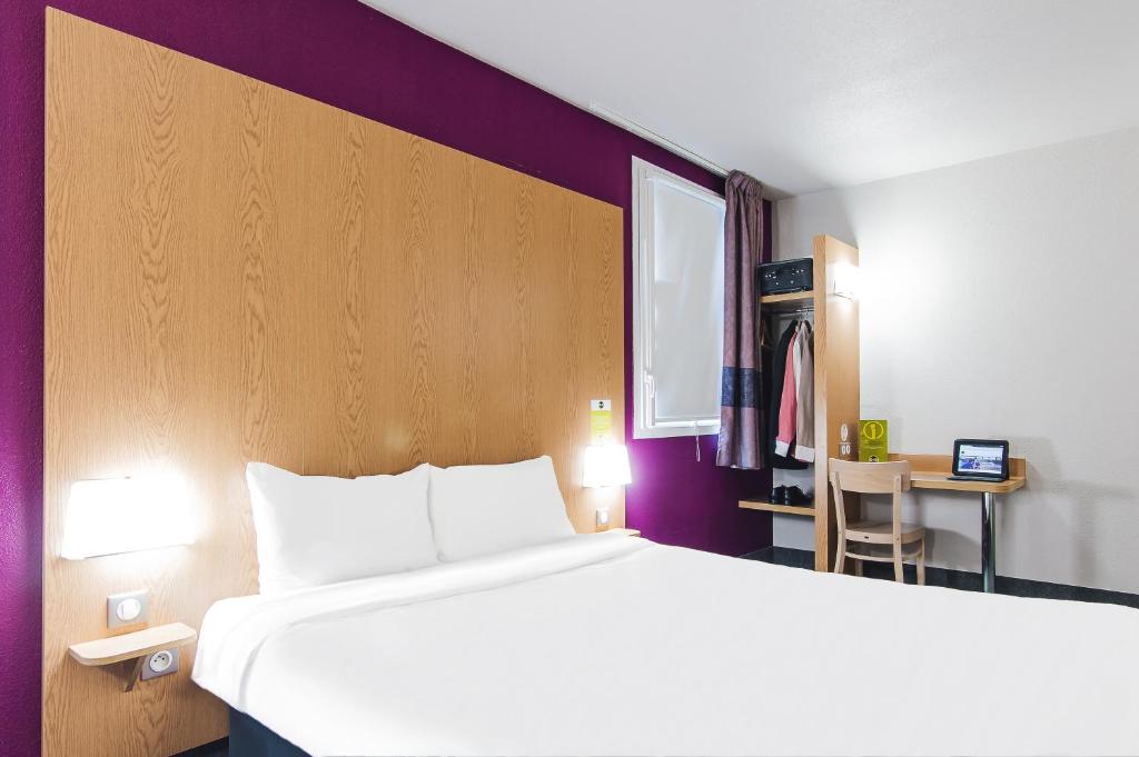 トゥールーズにあるB&B HOTEL Toulouse Purpan Zénithの大きなベッドとデスクが備わるホテルルームです。