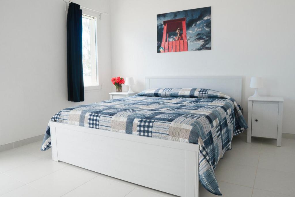 - une chambre blanche dotée d'un lit avec une couverture bleue et blanche dans l'établissement Centro Vacanze Lido Smeraldo, à Frigole