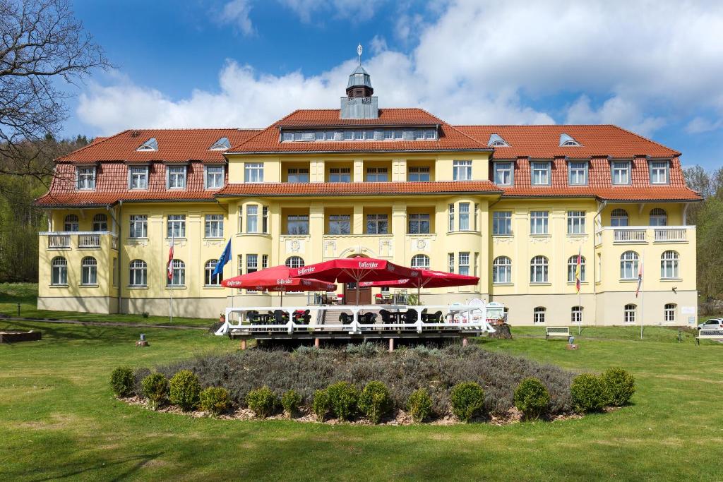 a large yellow building with umbrellas in front of it at Ferien Hotel Villa Südharz in Sülzhayn