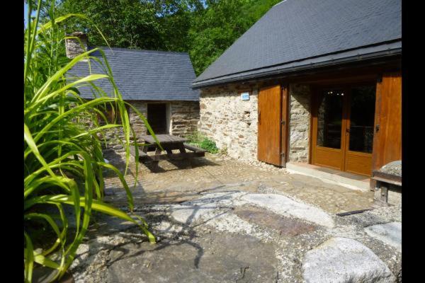 a stone building with a bench and a house at artiguelongue grange restaurée in Loudenvielle