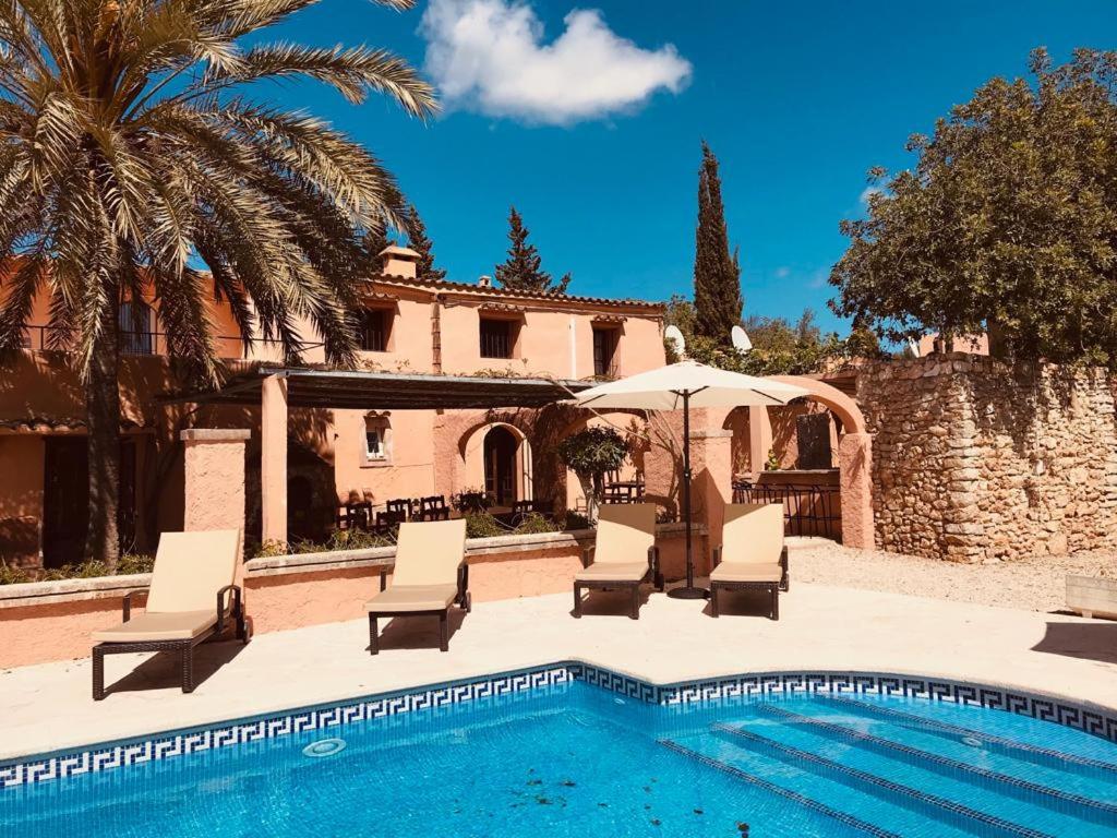 une piscine avec des chaises et un parasol ainsi qu'une maison dans l'établissement Finca Can Jordi, à Felanitx